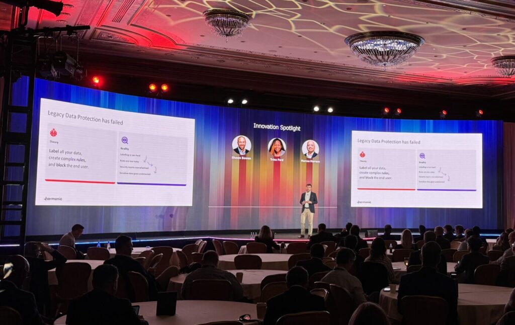 man speaking on a stage at a corporate conference